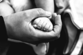 black-and-white-image-of-babys-foot-in-mans-hand